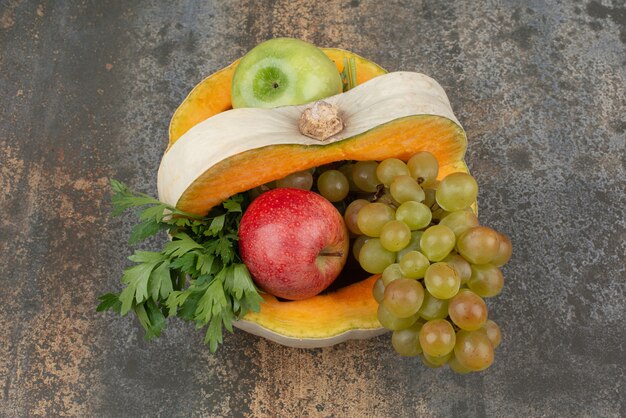 Pumpkin with apples and grapes on marble surface. 