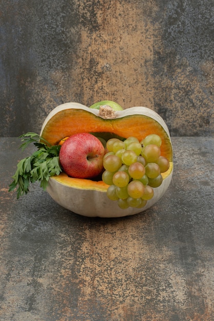 Pumpkin with apples and grapes on marble surface. 