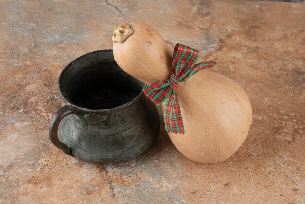 Pumpkin with bow and ancient kettle on marble.