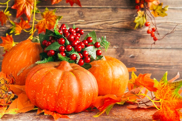 Pumpkins and berries among autumn leaves