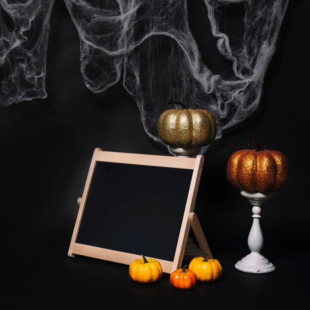 Pumpkins and chalkboard near Halloween decorations