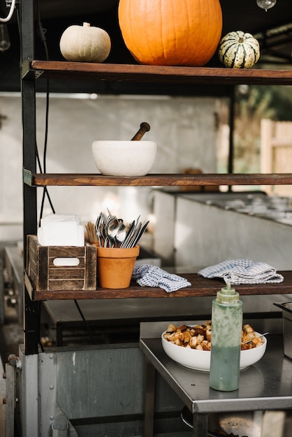 Pumpkins and kitchen utensils on a wooden shelf