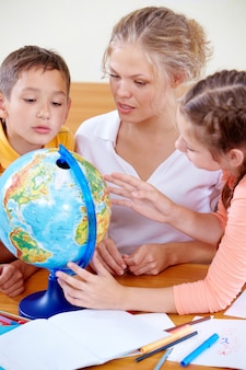 Учащиеся смотрят на глобус во время прослушивания учителя