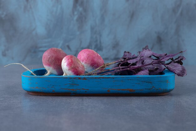 Purple basil with radishes on the board , on the marble surface.