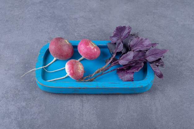 Purple basil with radishes on the board , on the marble surface.