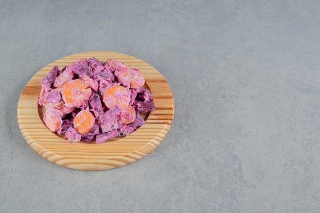 Фиолетовый салат из свеклы и моркови на деревянной доске.