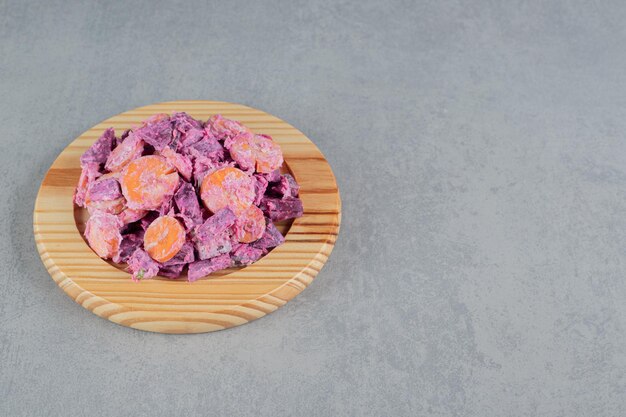 Purple beetroot and carrot salad on a wooden board.