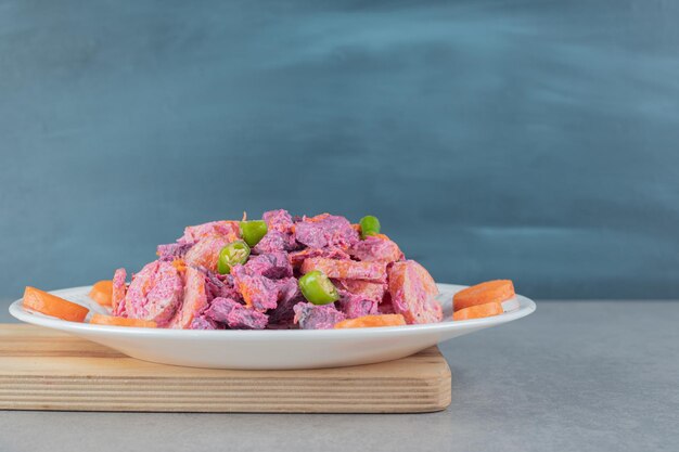 Purple beetroot and carrot salad on a wooden board.