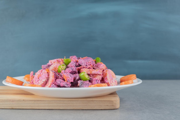 Фиолетовый салат из свеклы и моркови на деревянной доске.