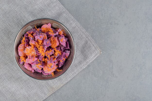 Purple beetroot salad wih carrot slices and sour cream in a metallic bowl