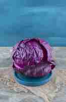 Бесплатное фото Фиолетовая капуста на деревянной тарелке, на подставке, на мраморном столе.