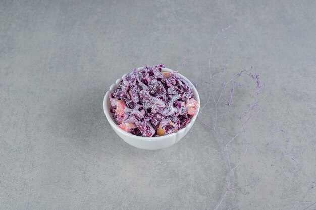 Салат из фиолетовой капусты и лука в керамической чашке.