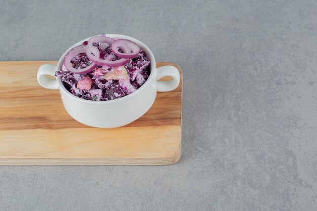 Purple cabbage and onion salad in a ceramic cup.