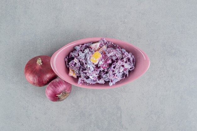 Purple cabbage and onion salad with various ingredients in ceramic cups.