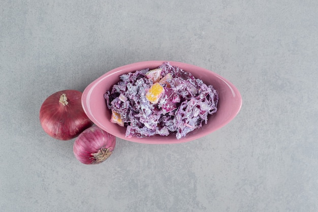 Салат из фиолетовой капусты и лука с различными ингредиентами в керамических чашках.