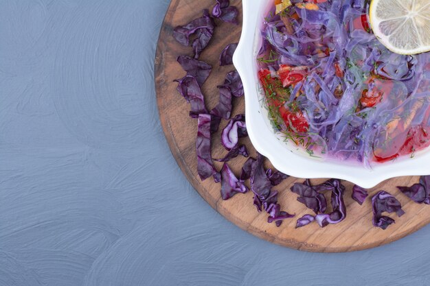 Purple cabbage soup in a white bowl on a wooden platter