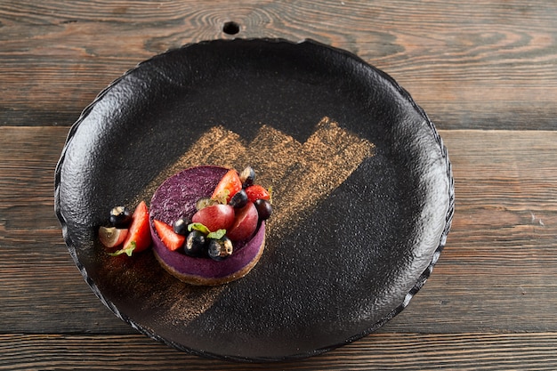 Фиолетовый чизкейк с ягодами на тарелке