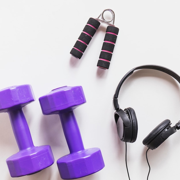 Purple dumbbells; headphone and hand grip on white backdrop