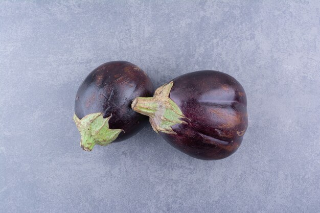 Purple eggplants isolated on blue surface