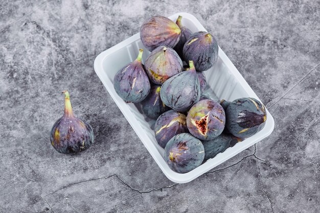 Purple figs in a white plastic container.