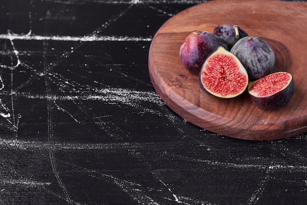 Free photo purple figs on a wooden platter.