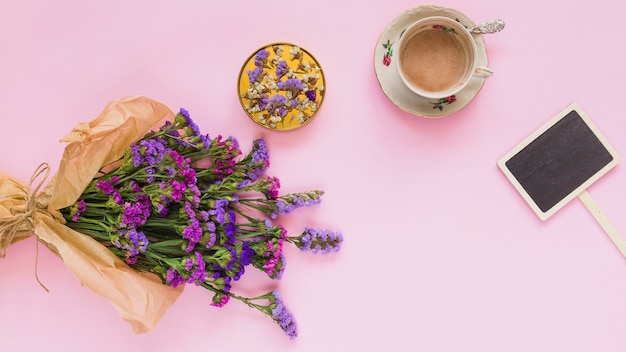 紫の花の花束;コースター;コーヒーカップ;ピンクの背景にプラカードラベル