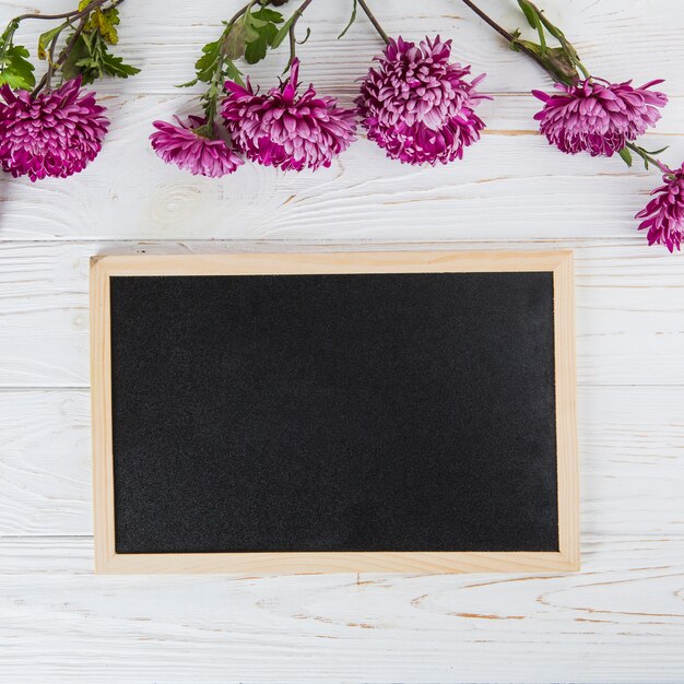 Purple flowers with blank chalkboard on wooden table