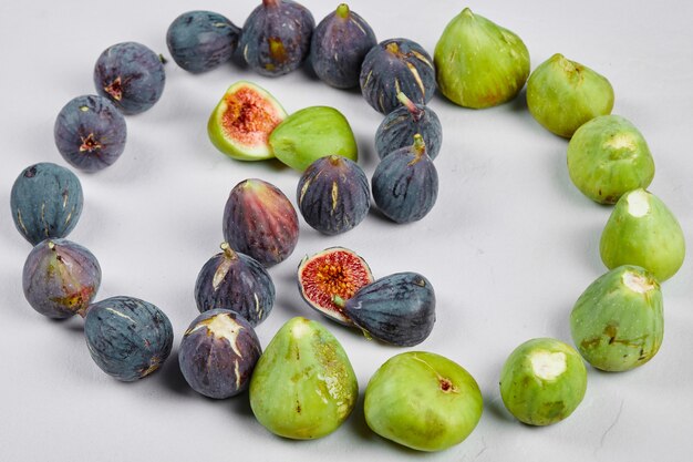 Purple and green figs scattered on white.