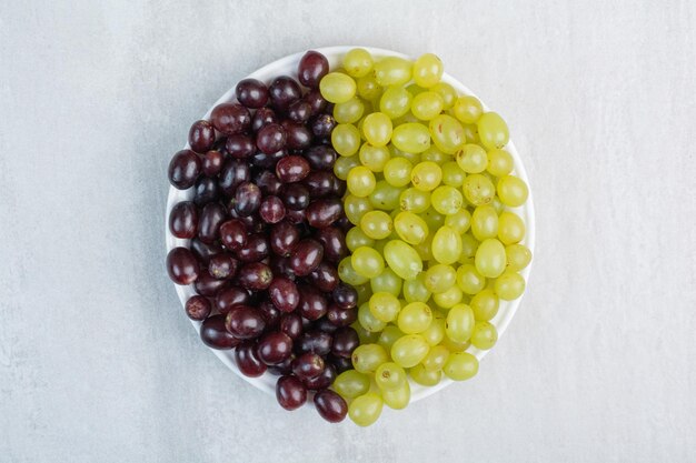 Purple and green grapes on white plate. High quality photo