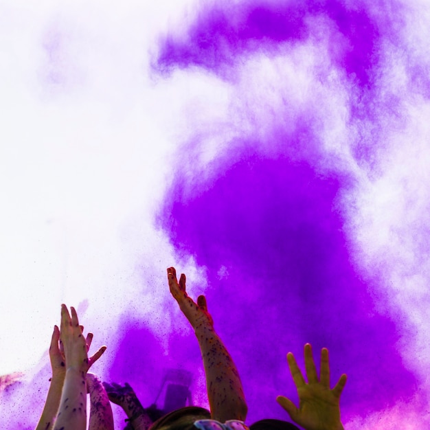 Colore viola holi sulle persone che alzano la mano ballando