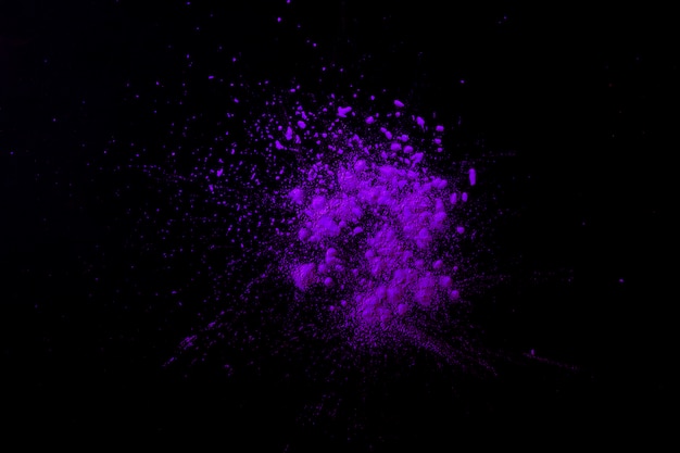 Фиолетовый индийский фестиваль цветных частиц на темно-черной поверхности