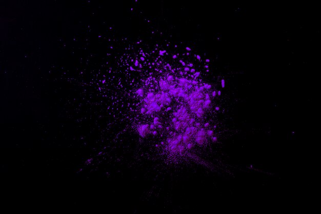 Purple indian festival color particles on dark black surface