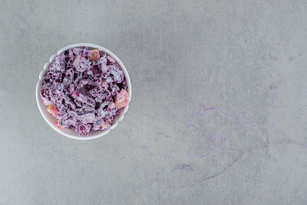 Purple onion salad in a ceramic cup on concrete surface