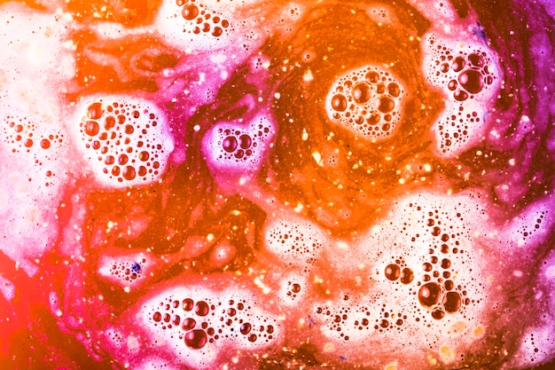 Free photo purple; orange and red foam after dissolving color bath bomb in water