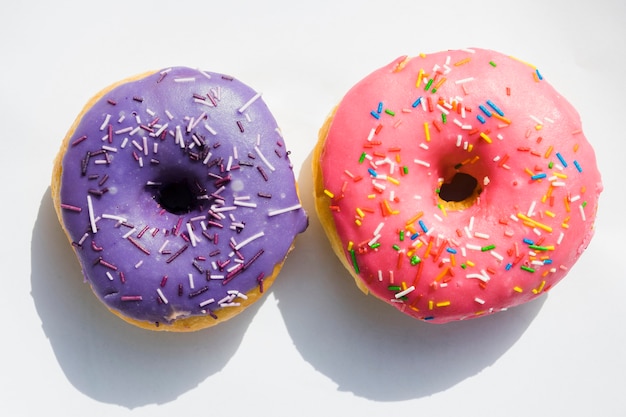 Purple and pink donuts on white background