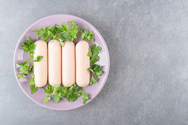 A purple plate of boiled sausages with parsley 