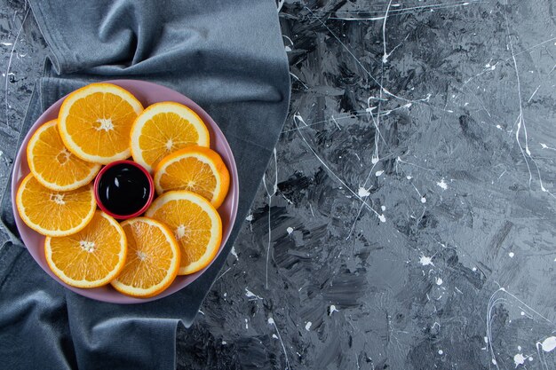 Purple plate of sliced juicy oranges on marble surface.