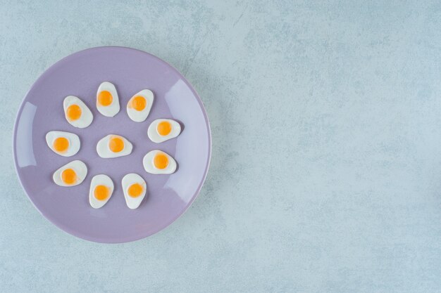달콤한 젤리 과자의 보라색 접시는 흰색 표면에 계란을 스크램블