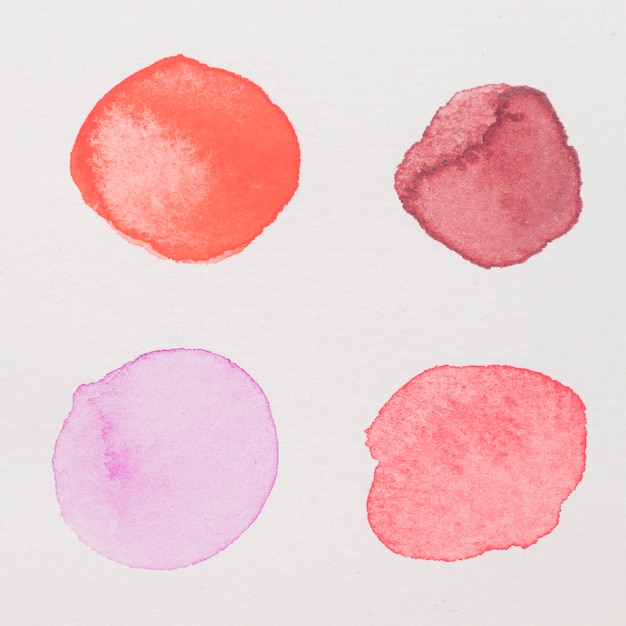 Purple, red, pink and crimson paints on white paper