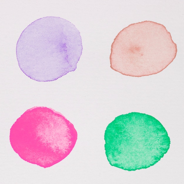Purple, red, pink and green paints on white paper