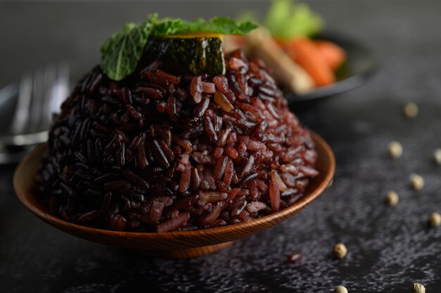 Purple rice berries cooked in a wooden dish with mint leaves.
