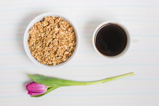 Purple tulips with bowl of oatmeal's and tea cup on white background