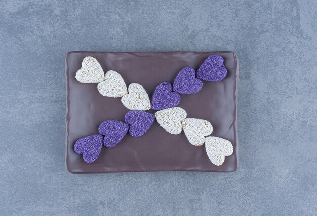 Purple and white cookies on the board , on the marble background. 