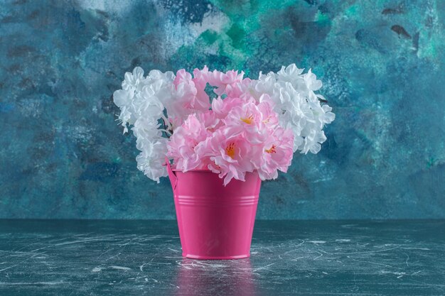 Purple and white flowers in a pink bucket , on the white background.