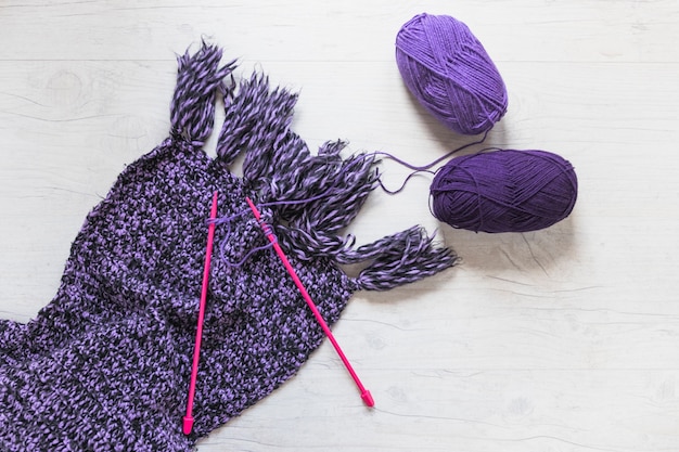 Purple yarn with knitted needles on woolen scarf