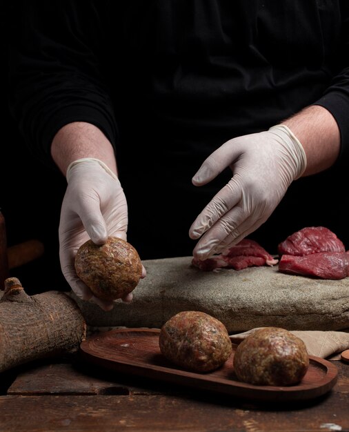 Putting ready meatballs into a wooden tray