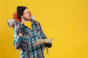 Free photo puzled young hiker with leather gloves and backpack holding map