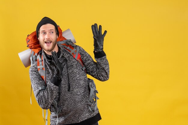 puzzed male hitchhiker with leather gloves and backpack staying away from something