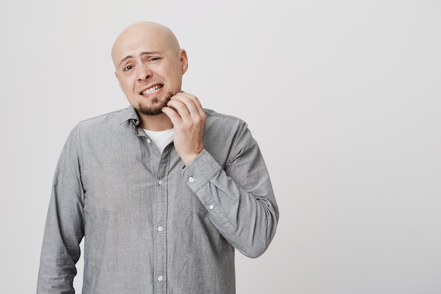 Puzzled bald man scratching beard, itching