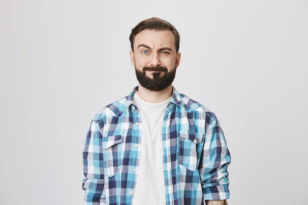 Free photo puzzled bearded funny guy making confused face
